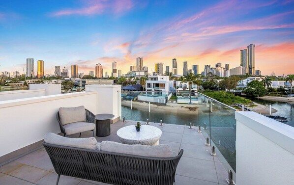 A rooftop terrace with outdoor seating, a pool, and a city skyline view.