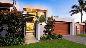 Une maison moderne avec un garage, une pelouse bien entretenue et une variété de plantes.
