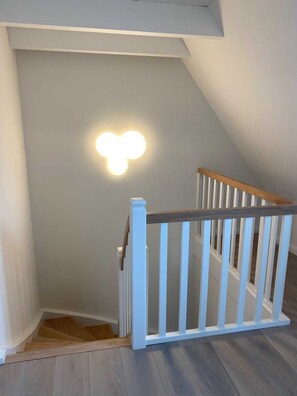 A staircase with a white railing and a light fixture on the wall.