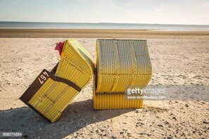 Two yellow beach chairs on a sandy beach with a clear view of the ocean in the background.
