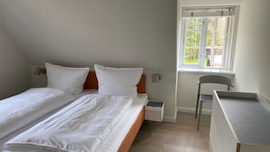 Un dormitori amb llit, escriptori, cadira, finestra i tauleta de nit.