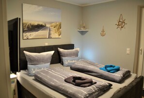 A bedroom with two beds, a television, and nautical-themed decor.