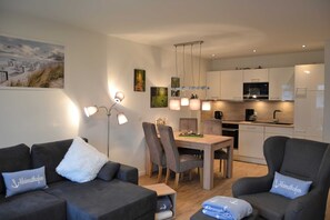 A modern living room with a dining area, a kitchen, and a large window.