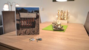 A room with a wooden table displaying a framed photograph, a decorative sculpture, and a set of keys. - App. Ankerplatz mit 2 SZ und 2 Balkonen - Appartement mit 2 SZ (Kellenhusen (Ostsee))