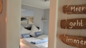 A bedroom with a bed, pillows, and a wall-mounted sign with text. - App. Ankerplatz mit 2 SZ und 2 Balkonen - Appartement mit 2 SZ (Kellenhusen (Ostsee))