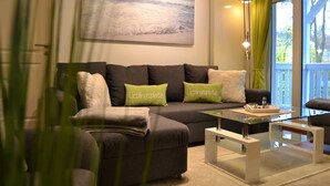 A modern living room with a sofa, a glass coffee table, and a painting on the wall. - Resid. Prorer Wiek App. 7, Strandnah in Binz, mit Balkon - App. mit 1 SZ + 1 Schlafkoje - Aufbettung (Binz)