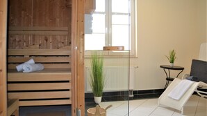 A wooden sauna room with benches, a small table with a plant, and a chair with a towel. - Resid. Prorer Wiek App. 7, Strandnah in Binz, mit Balkon - App. mit 1 SZ + 1 Schlafkoje - Aufbettung (Binz)