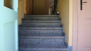 A staircase with a handrail, a door at the top, and a wall with a textured finish.