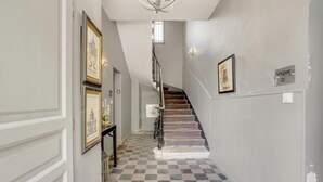 A hallway with a checkered floor, a staircase, and framed artwork on the walls. - Beautiful Loft Apartement, quiet, 5 mn historical center (Isle sur la Sorgue)