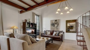A spacious living room with a sofa set, a coffee table, a bookshelf, and a large painting. - Beautiful Loft Apartement, quiet, 5 mn historical center (Isle sur la Sorgue)