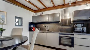 A modern kitchen with stainless steel appliances, a dining table with chairs, and a wooden ceiling. - Beautiful Loft Apartement, quiet, 5 mn historical center (Isle sur la Sorgue)