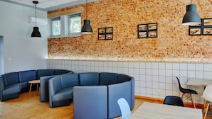 A modern interior with a brick wall, blue seating, and pendant lighting. - Morski Park Międzywodzie (Dziwnów)