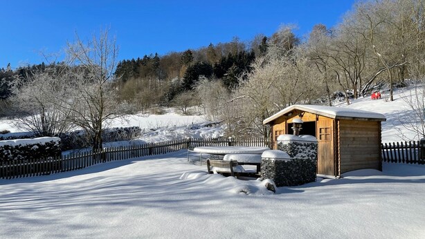 A wooden cabin with a snow-covered roof, surrounded by a wooden fence and snow-covered ground. - Your own home in the Sauerland, relax if you can! (Willingen)