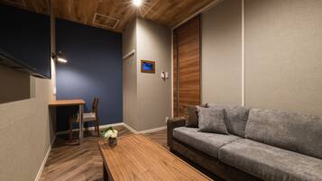 A modern living room with a wooden ceiling, a grey sofa, a wooden coffee table, and a small table with chairs.
