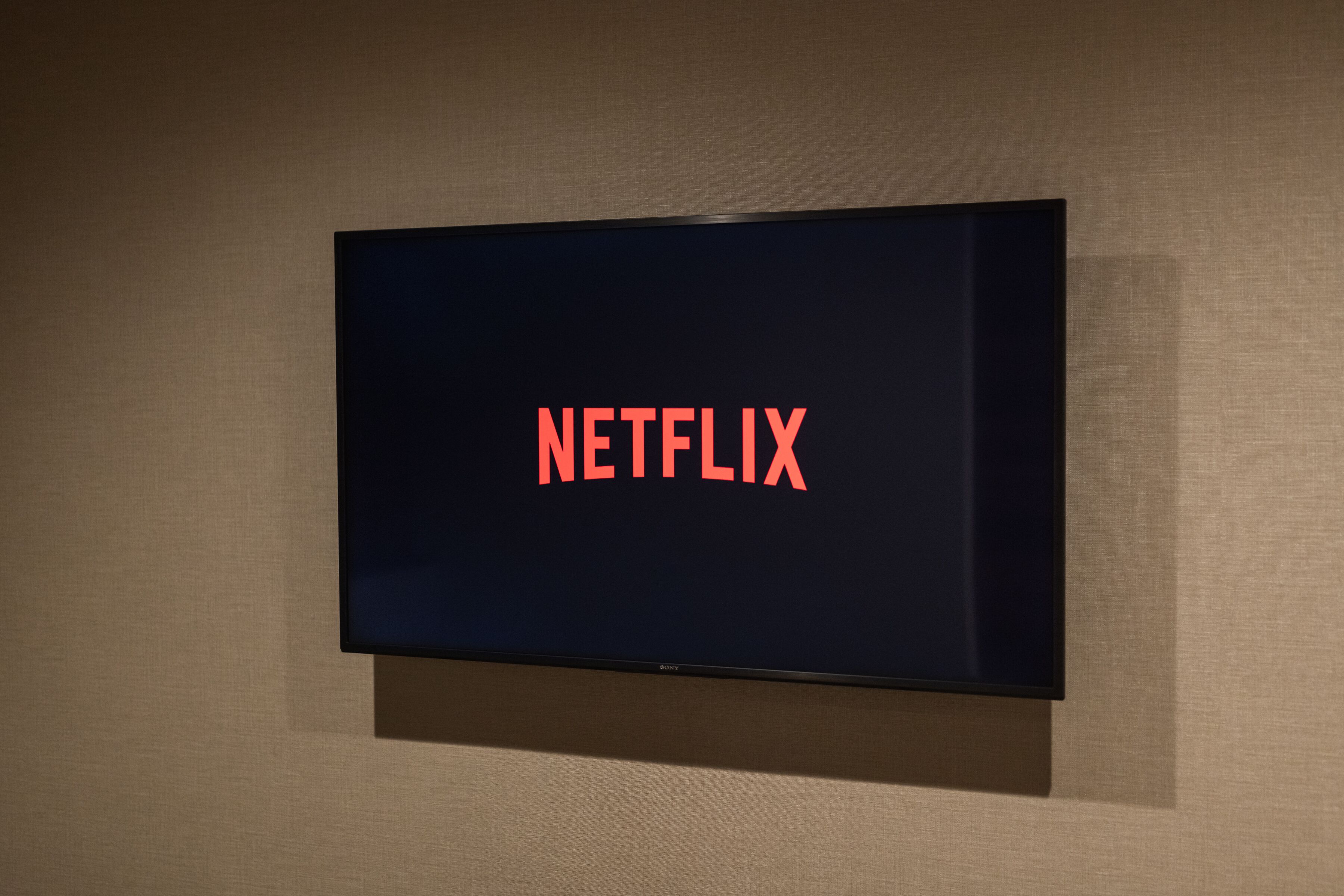 En platt-TV som är monterad på en vägg och som visar Netflix-logotypen.