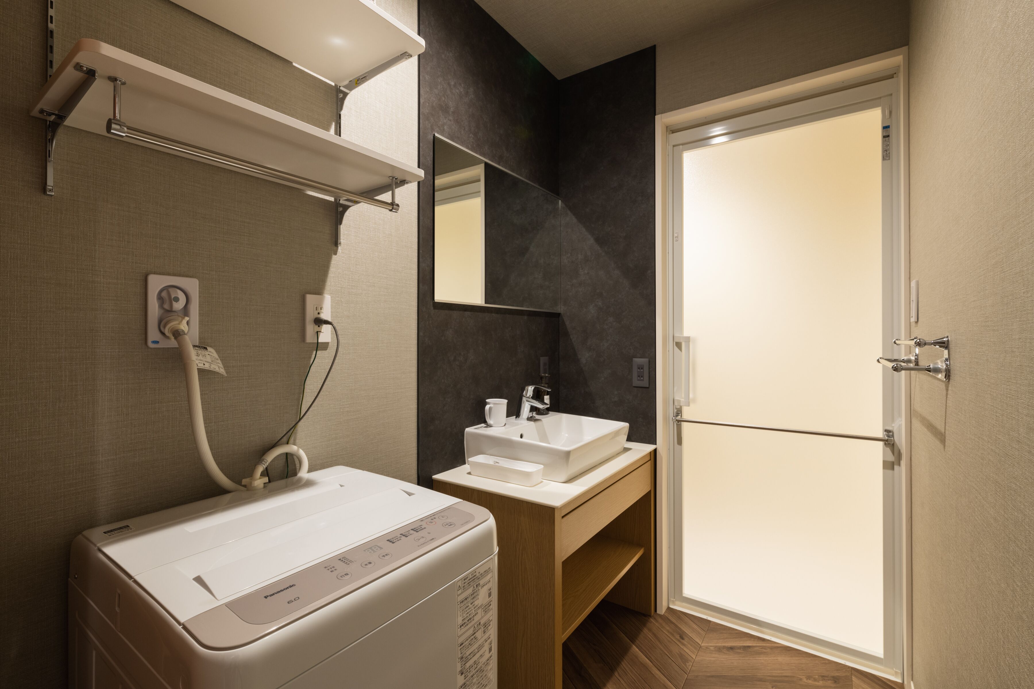 A modern bathroom with a built-in washing machine, a sink, and a mirror.