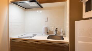 Una cocina moderna con azulejos blancos, una campana extractora de acero inoxidable, una cafetera y un lavavajillas integrado.