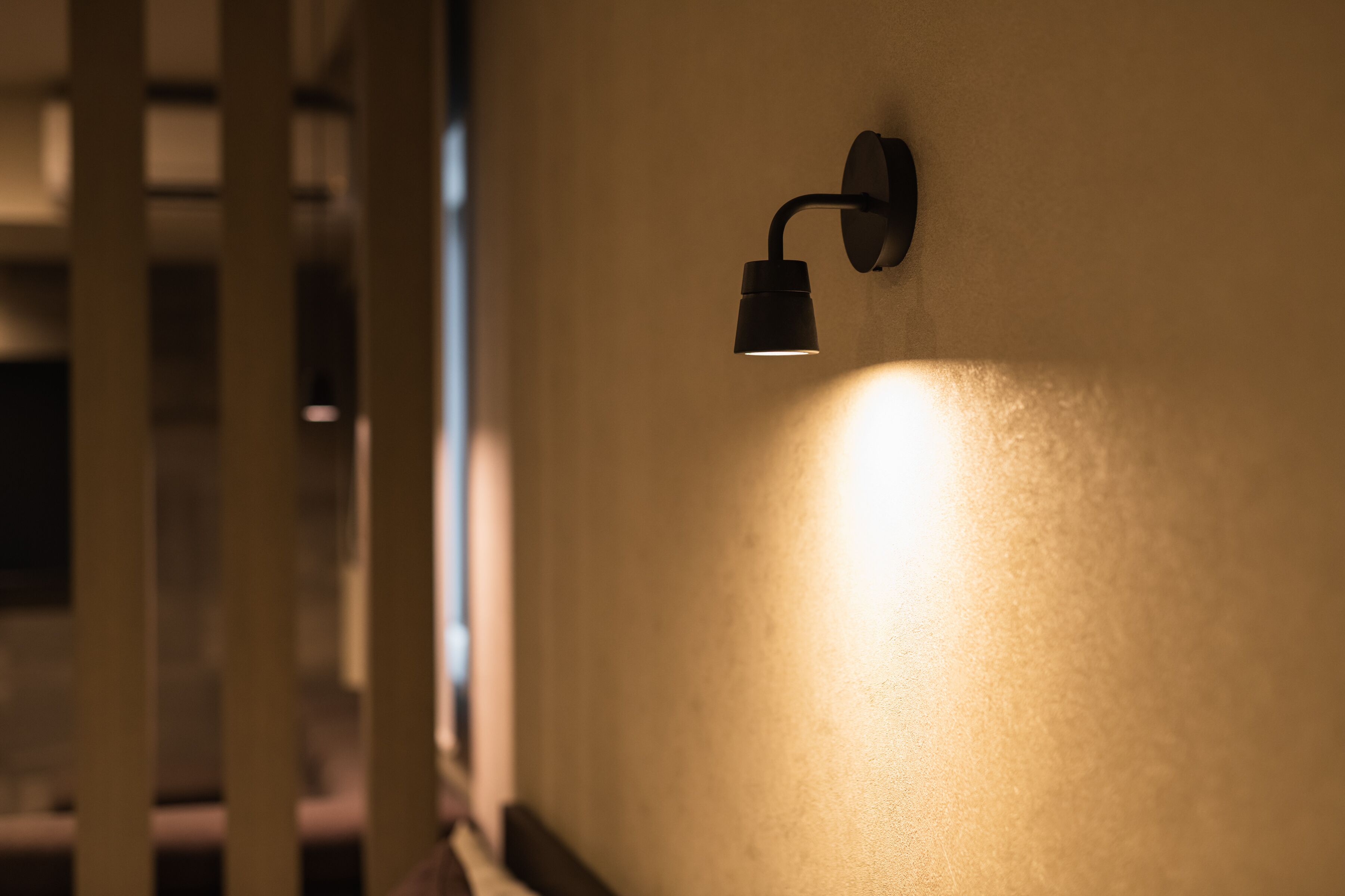 Een wandlamp die een warme gloed werpt op een structuurwand.