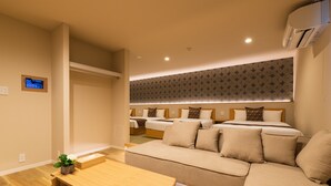 A modern hotel room with a sofa, a wooden table, and a small plant. - GRAND BASE Saiwaimachi (Nagasaki)