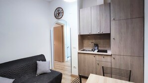 A compact living space with a kitchenette, a sofa, and a dining table. - Antica Assisi Apartment - in the Historic Center with Bedroom, Bath and Kitchen (Assisi)