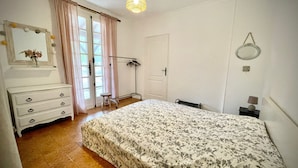 Un dormitorio con cama, cómoda, espejo y ventana con cortinas.