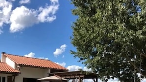 Una casa con techo de tejas, mobiliario exterior y jardín con macetas.