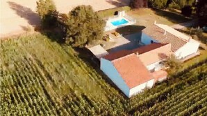 Vista aérea de una casa con piscina, rodeada por un jardín cuidado y campos.