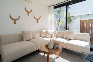 Una sala de estar moderna con un sofá seccional color beige, una mesa de centro de madera y cuernos de madera decorativos en la pared.