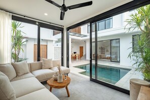 Una sala moderna con un sofá, una mesa de centro y vistas a la piscina.