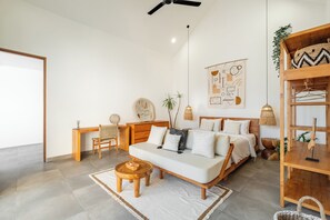 A modern bedroom with a bed, a sofa, a desk, and a hanging plant. - Villa Ziggy (Canggu)