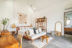 A modern bedroom with a wooden bed, a bedside table, a hanging lamp, a mirror, and a wall-mounted shelf with decorative items. - Villa Ziggy (Canggu)