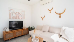 A modern living room with a flat-screen TV, a wooden console, a beige sofa, and decorative wall art.