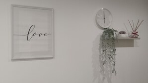 A framed word "love" on a wall, a clock, and a shelf with a plant and decorative items. - "Serenity" room - second floor attic (Palo del Colle)