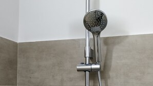 A shower with a handheld showerhead and a rain shower attachment. There are two bottles of shampoo on a shelf below the shower. - "Serenity" room - second floor attic (Palo del Colle)