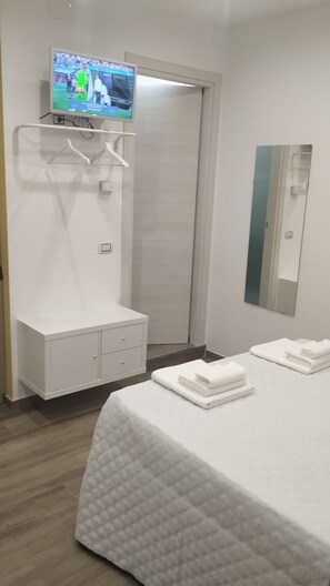 Ein Hotelzimmer mit Bett, Wandfernseher, Kleiderschrank und Spiegel.