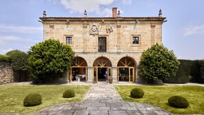 A stone building with a central courtyard, arched doorways, and a symmetrical facade.