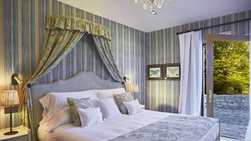 A bedroom with a large bed, striped wallpaper, and a view of greenery outside.