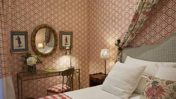 A bedroom with a checkered bedspread, a desk with a chair, a mirror, and framed pictures on the wall.
