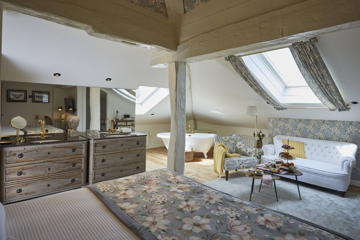 A bedroom with a skylight, a white sofa, a floral bedspread, and a dresser with drawers.