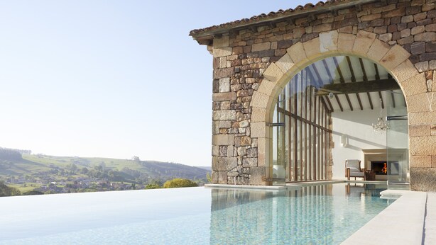 A stone building with an infinity pool and a view of the countryside.