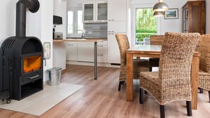 Una cucina moderna con mobili bianchi, forno integrato e zona pranzo con sedie in vimini e tavolo in legno.