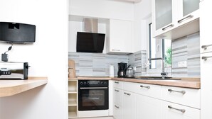 Una cucina moderna con mobili bianchi, forno a incasso e macchina da caffè.
