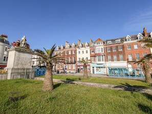 A historic building with a statue, palm trees, and a clear blue sky. - The Kings Vista (Weymouth)