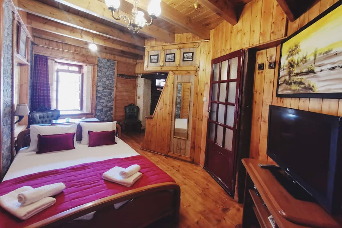 Een houten kamer in blokhutstijl met een bed, een televisie en een schilderij aan de muur.