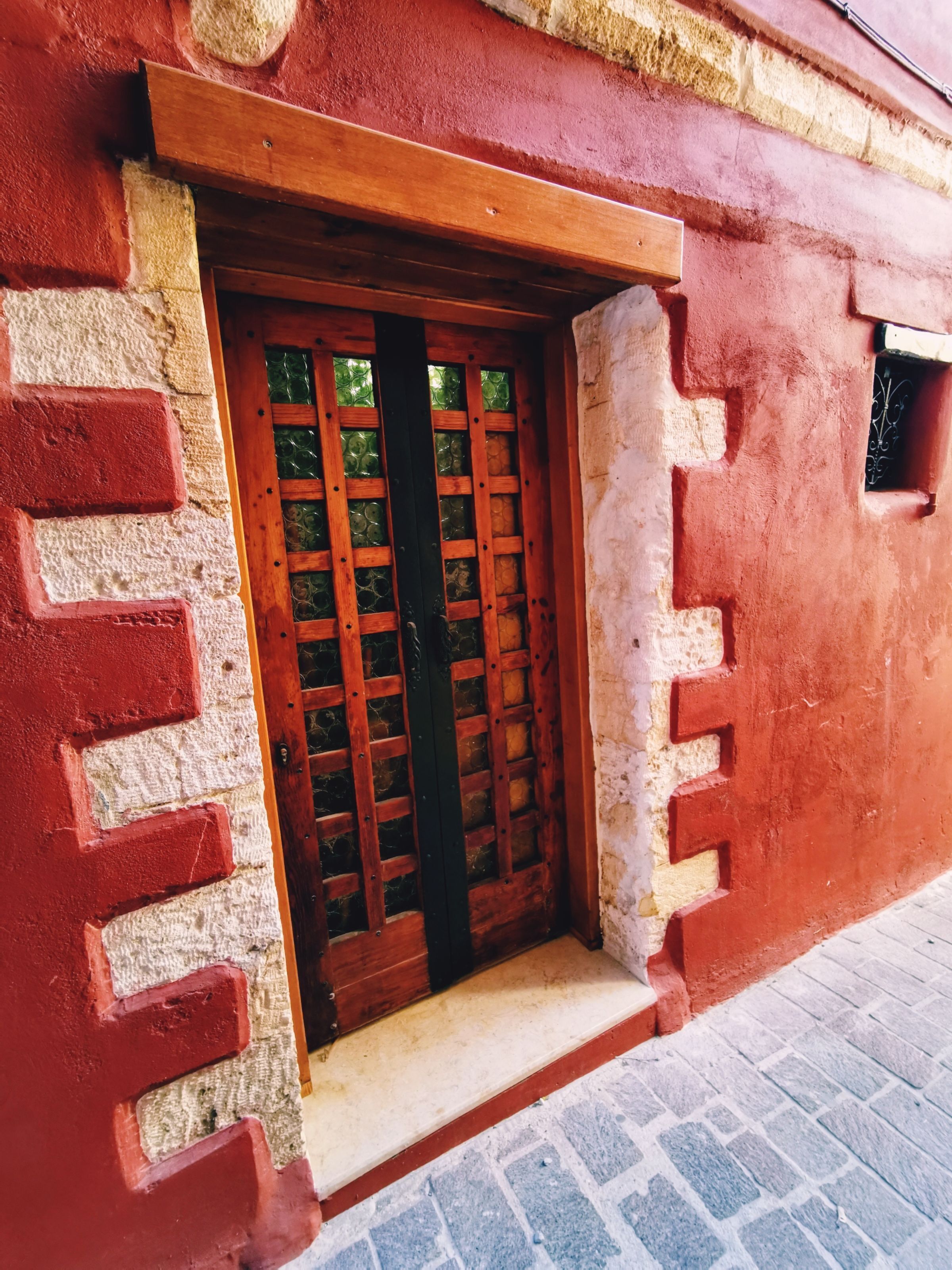 A red brick building with a wooden door featuring a grid pattern.