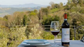 A table with a bottle of Riddell Rosso di Montagna wine, a glass of wine, and a plate with a fork and knife.