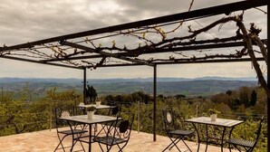 Ein überdachter Außenbereich mit Tisch und Stühlen, der einen schönen Ausblick bietet.