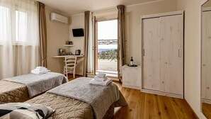 Ein Zimmer mit zwei Betten, einem Schreibtisch, einem Stuhl, einem Fernseher und einem Kleiderschrank.
