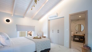Un dormitorio moderno con cama, mesita de noche, armario y baño a la vista a través de una puerta abierta.