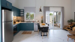 Una cocina moderna con armarios color turquesa, un refrigerador de acero inoxidable y una zona de comedor con mesa y sillas.